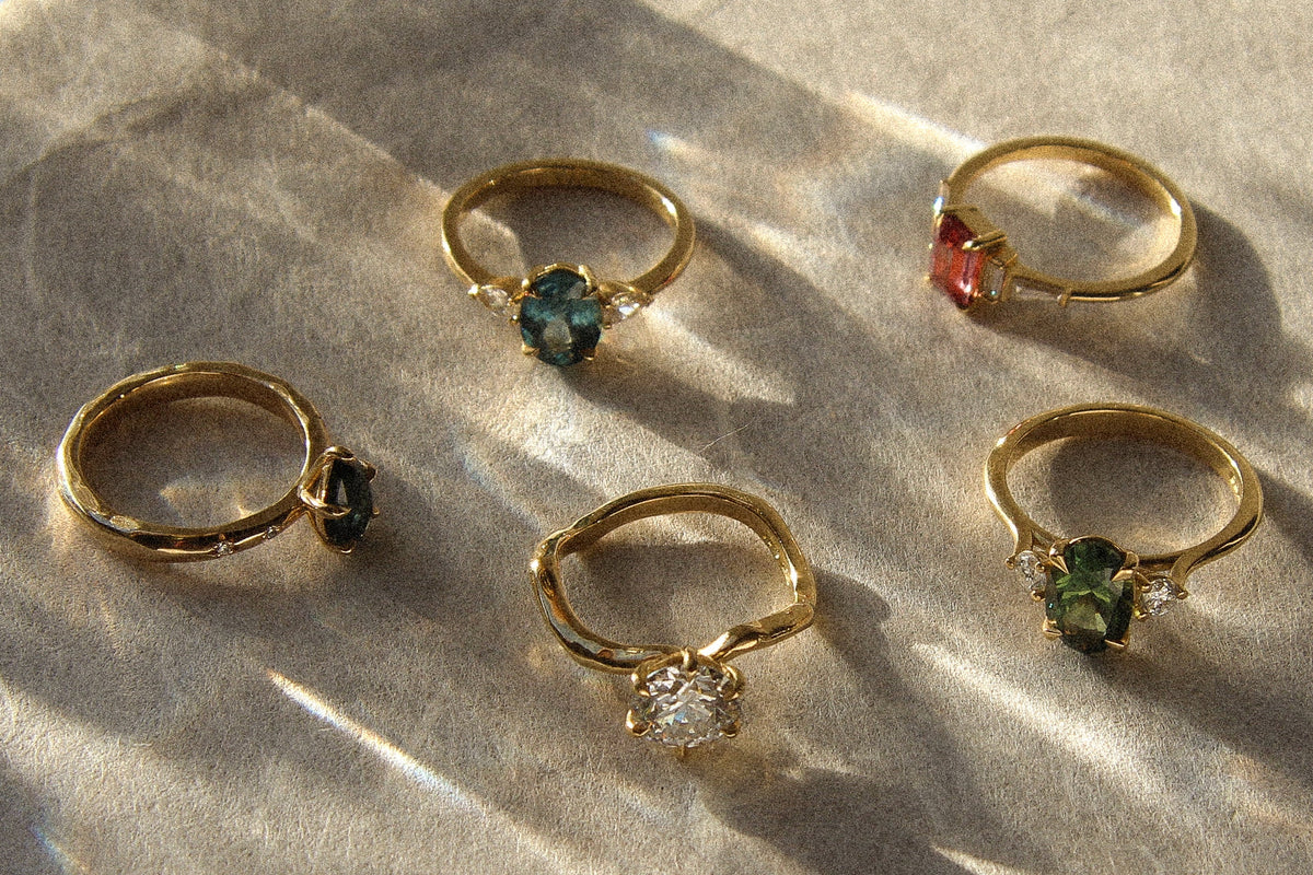 Gold rings with gemstones on a textured surface
