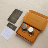 Two silver tins with jewellery imprint wax in an open orange box on a beige surface