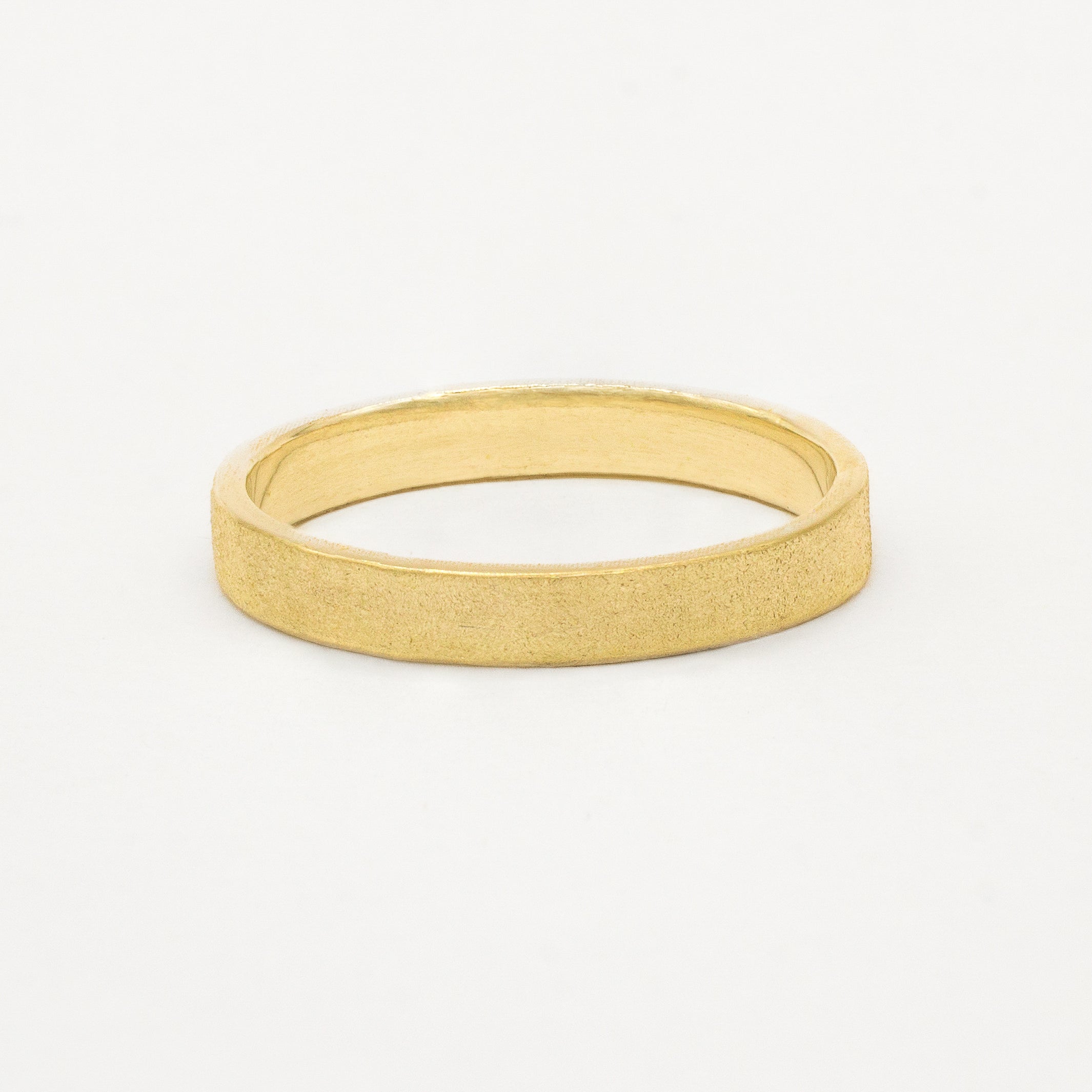 3mm wide frosted flat wedding ring in yellow gold on white background