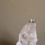 silver topaz ring balancing on top of a white crystal with a beige background