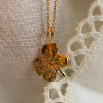 close up of solid gold pendant in 4 leaf clover shape on lace fabric 