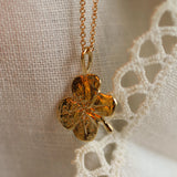 close up of solid gold pendant in 4 leaf clover shape on lace fabric 