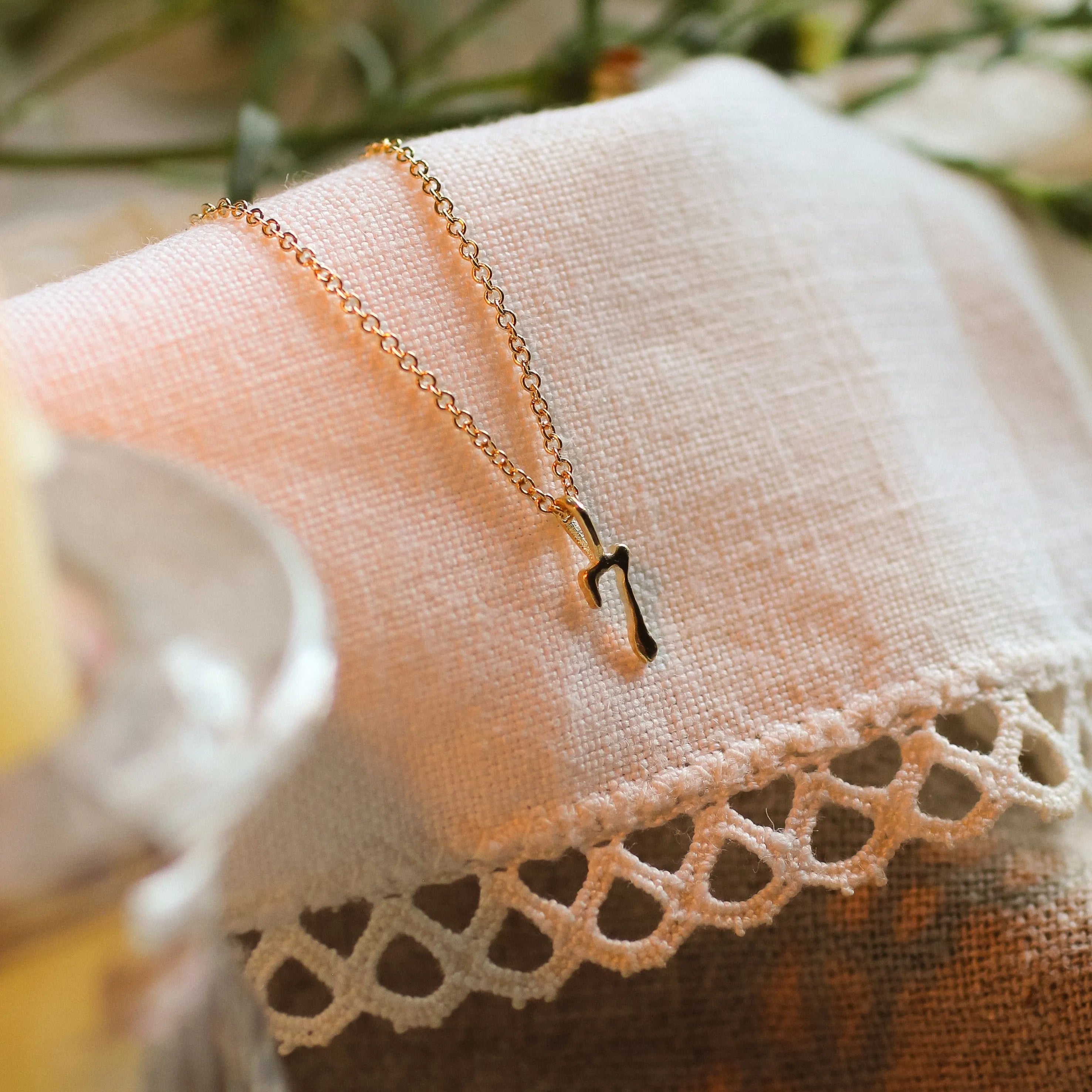solid gold necklace with 7 pendant on lace fabric