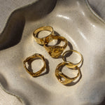 five gold rings on a textured stone surface
