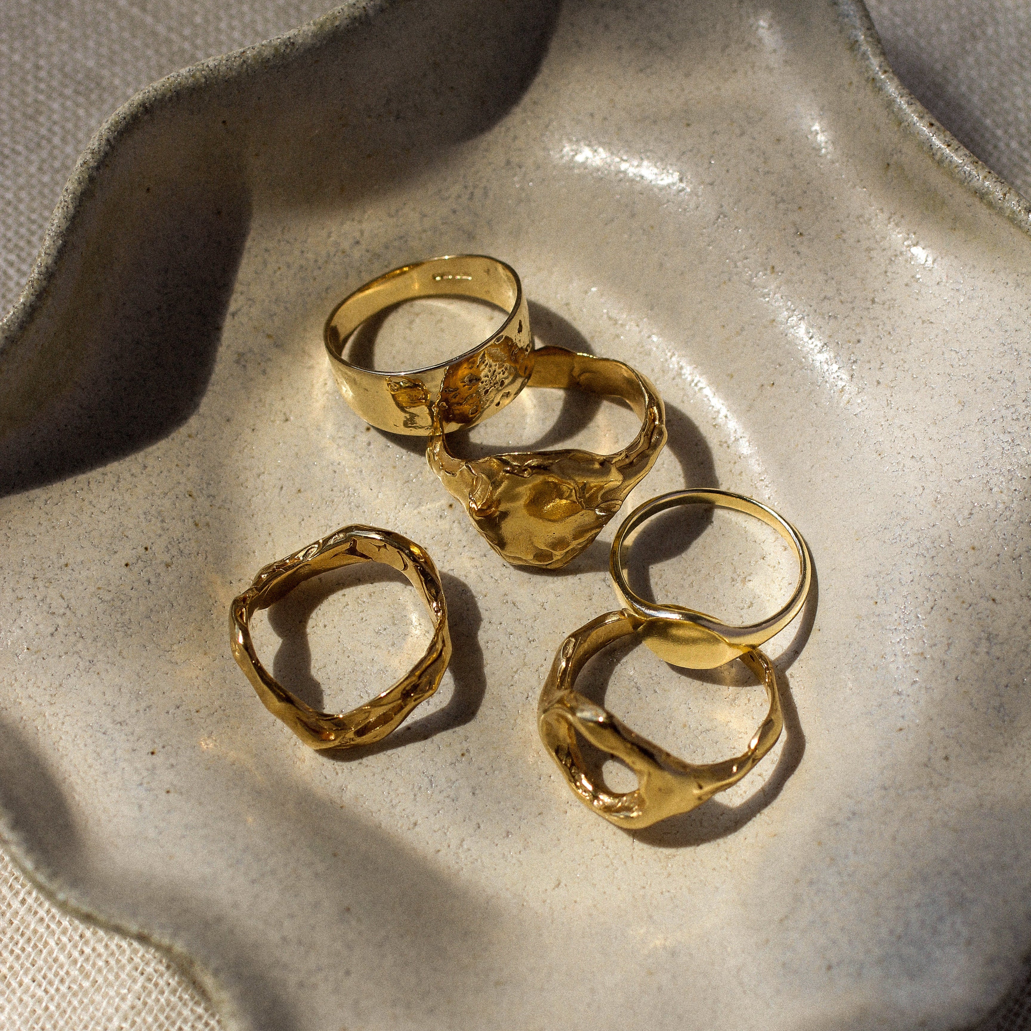 five gold rings on a textured stone surface