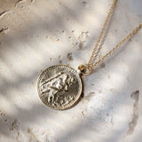 Gold st christopher necklace with a coin pendant on a textured surface