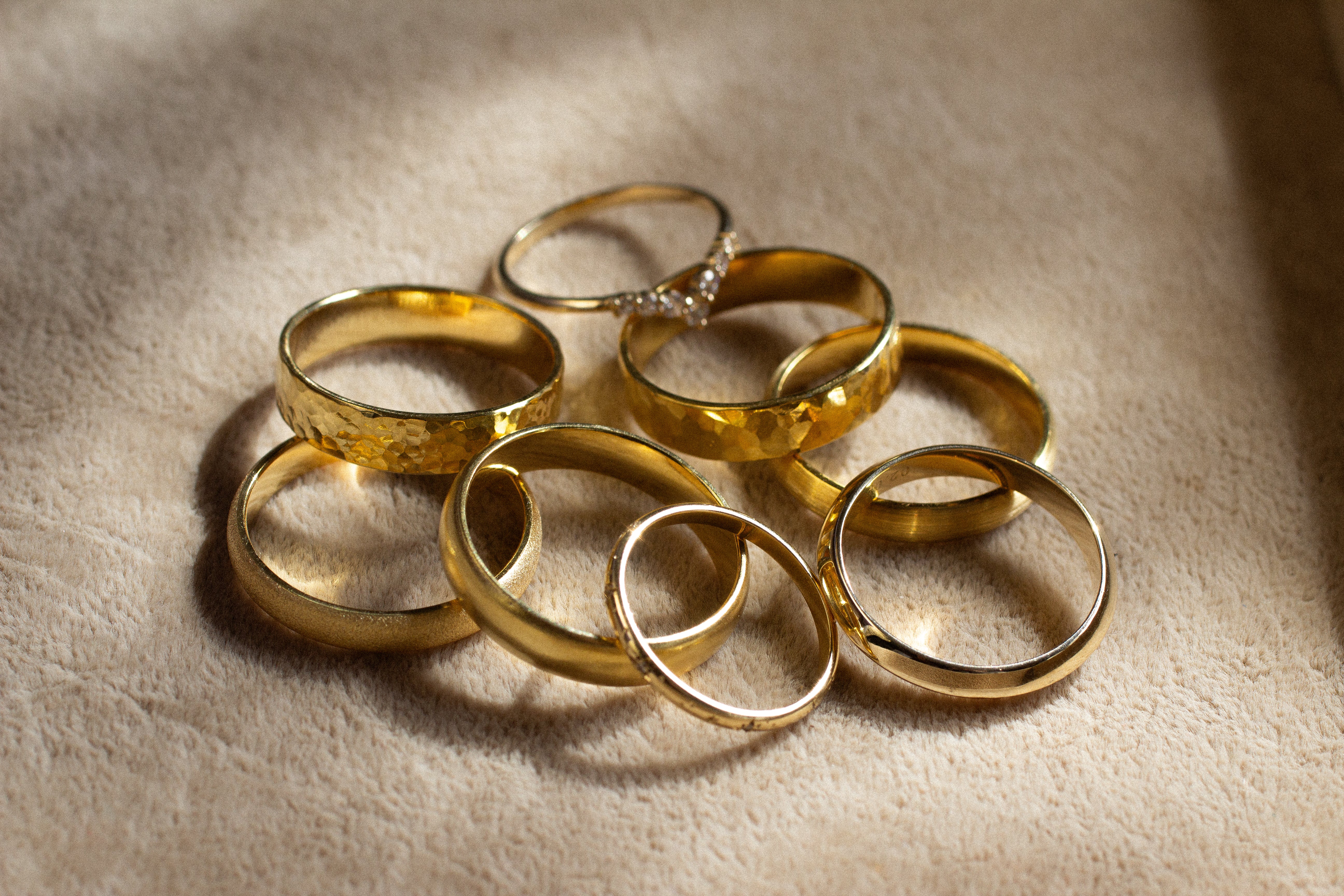 gold wedding rings of different textures in a pile of beige surface
