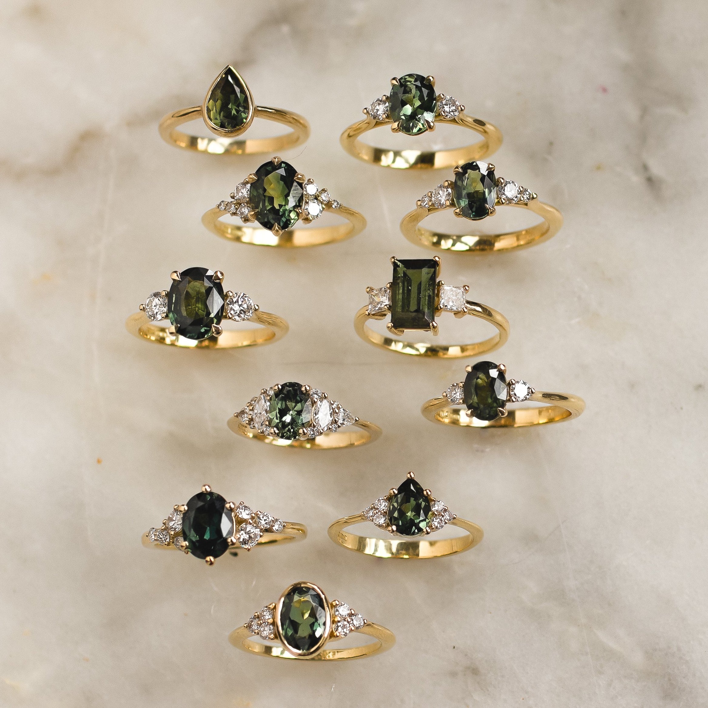 eleven green sapphire engagement rings on marble surface