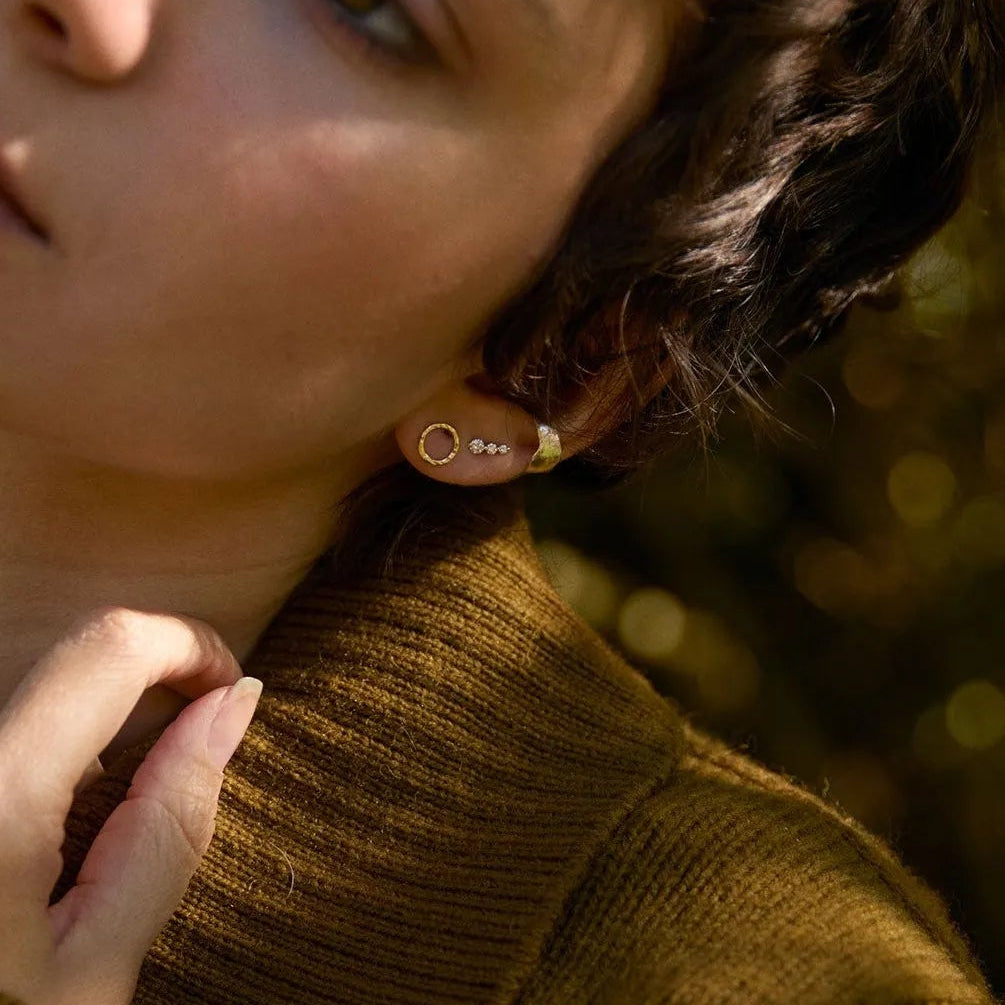 model outside wearing dark green jumper and circle earrings with diamond studs