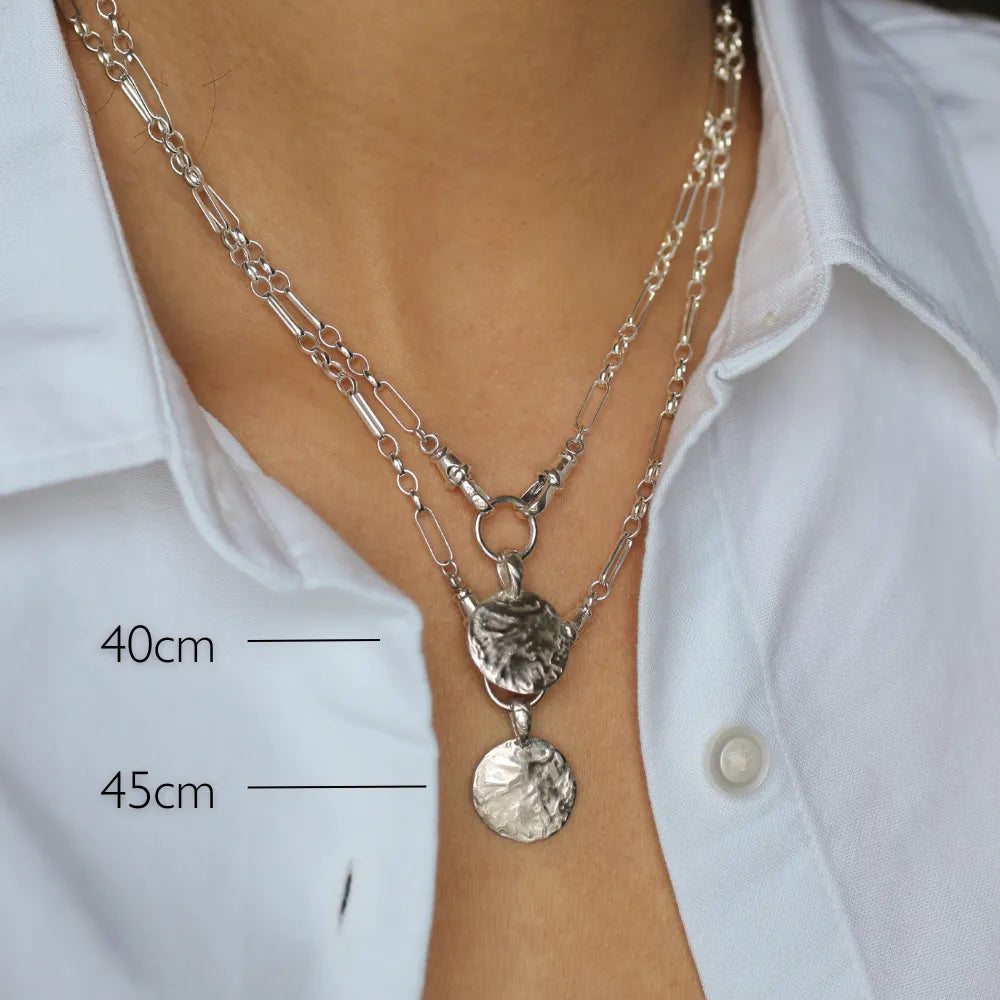 Silver necklace with pendant on a person wearing a white shirt, showing measurements.