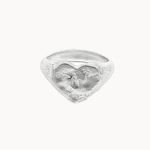 A textured sterling silver ring featuring a sculpted heart design and organic finish, photographed against a solid off-white background.