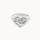 A textured sterling silver ring featuring a sculpted heart design and organic finish, photographed against a solid off-white background.