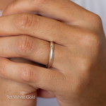 Close-up of a hand wearing a 9ct white gold ring with knife edge profile on a plain background