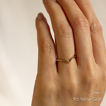Hand wearing a 9ct yellow gold chevron wedding ring with '2mm' text on a neutral background