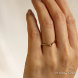 Hand wearing a 9ct yellow gold chevron wedding ring with '2mm' text on a neutral background