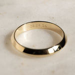 Gold ring with engraved text on a light marble background