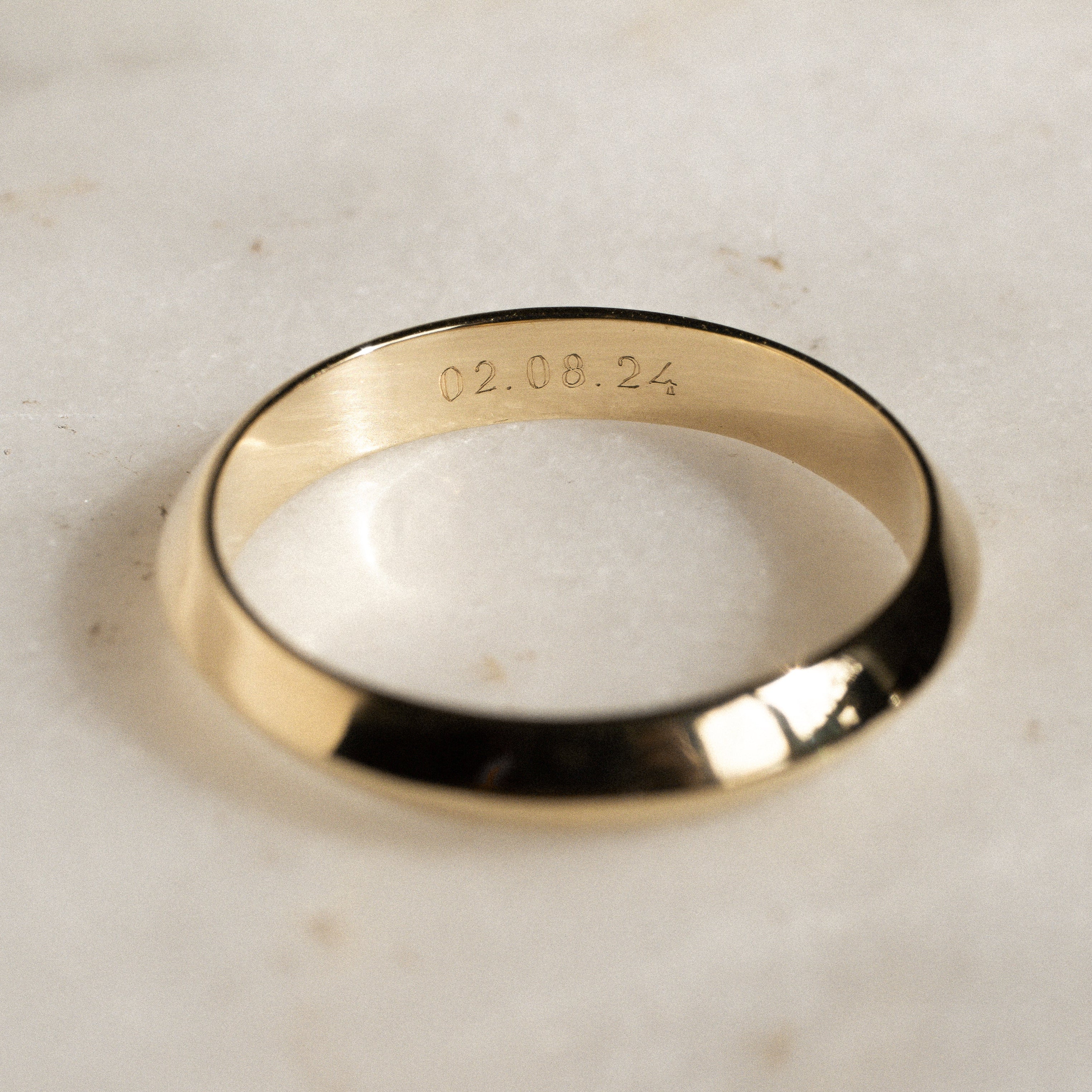 Gold ring with engraved text on a light marble background