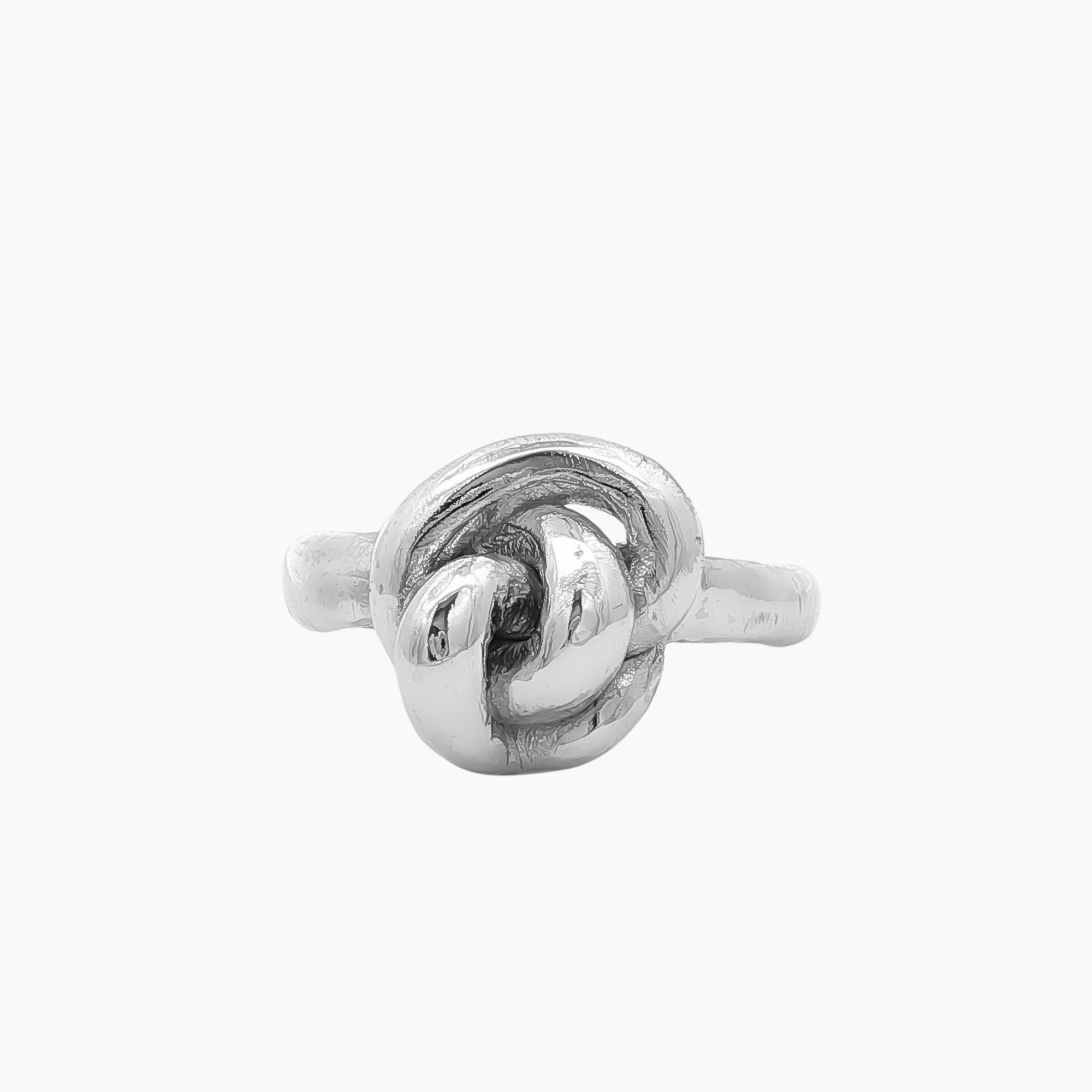 A polished silver ring featuring a sculpted knot design on a plain, light off-white background.