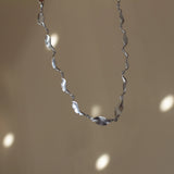 silver leaf chain necklace in motion with disco ball reflections in background