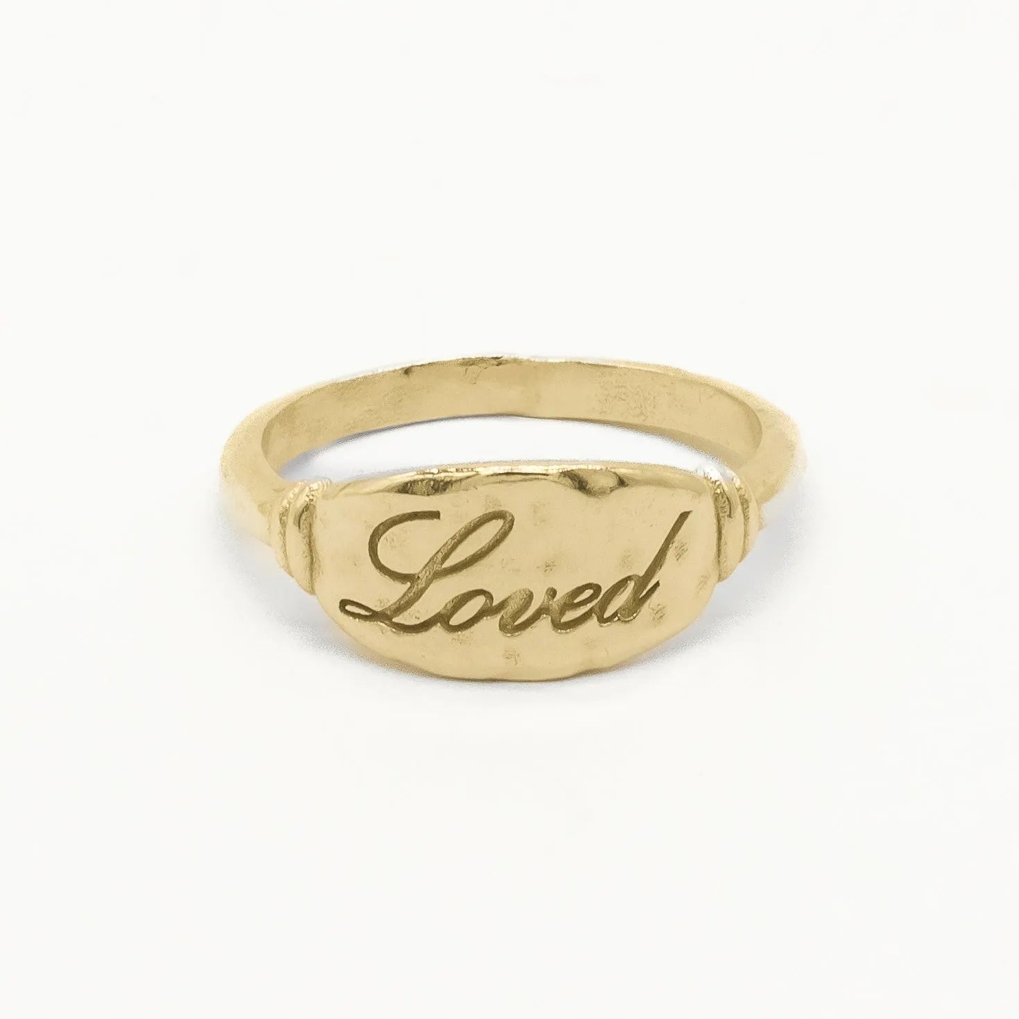 solid gold word ring with the word Loved engraved on a white background