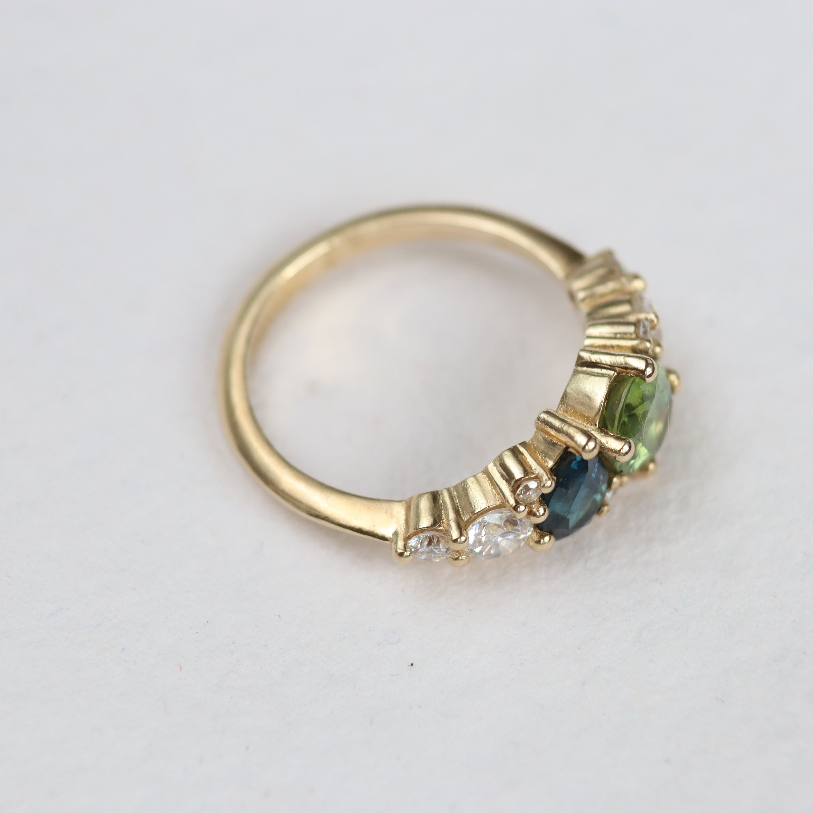 gold low-set engagement ring ring with three gemstones on a light gray background