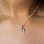 close up of someone wearing a silver necklace with star and number '8' pendants on the same chain