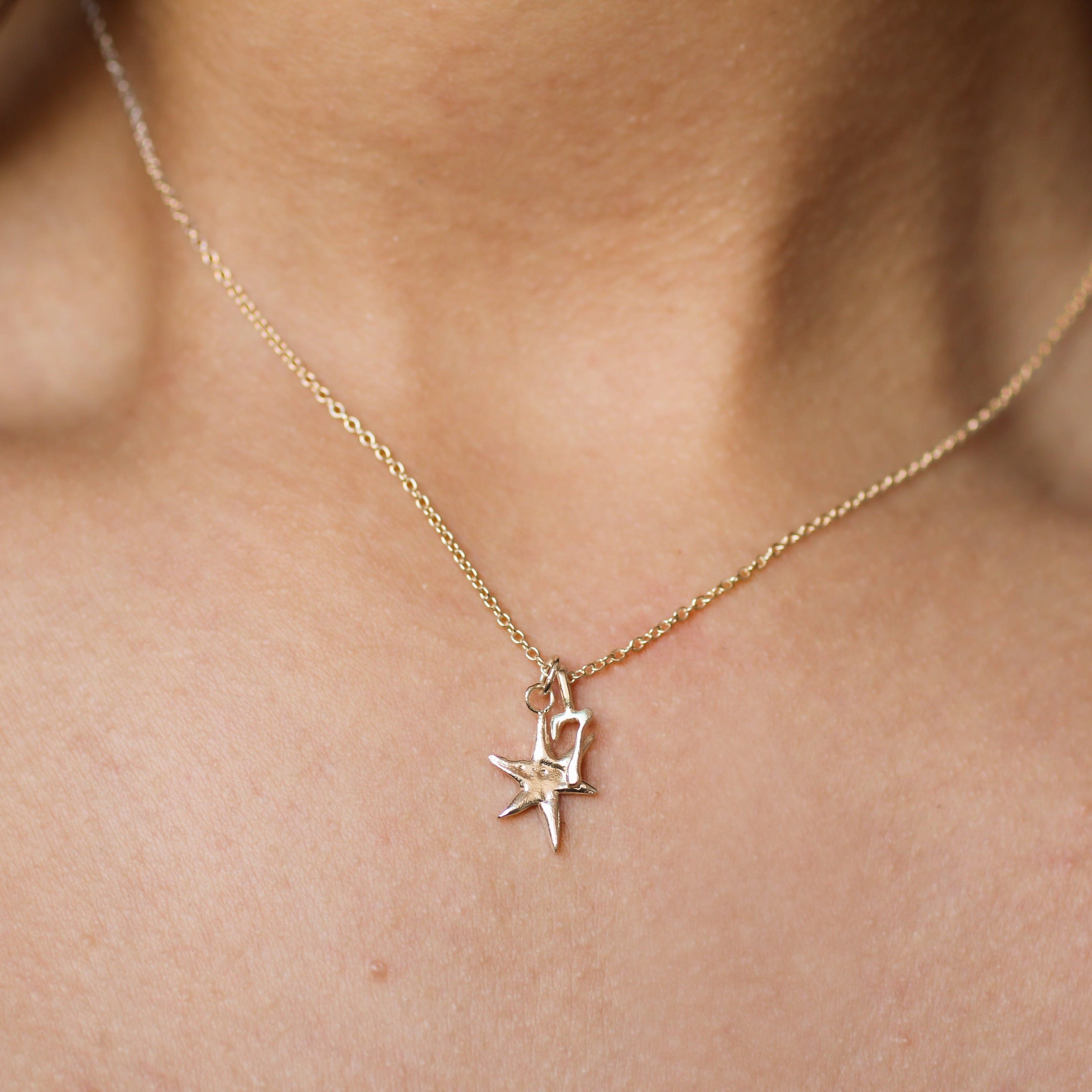 close up of person wearing a gold necklace with star and number '7' pendant on the same chain