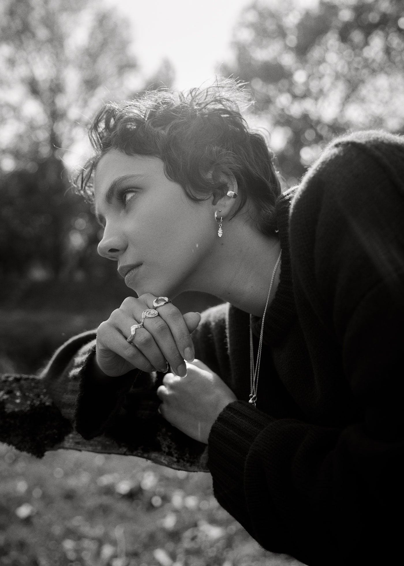 Black and white photo of a person sitting outdoors with trees in the background