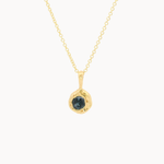 Gold necklace with a pendant featuring a dark blue sapphire on a white background