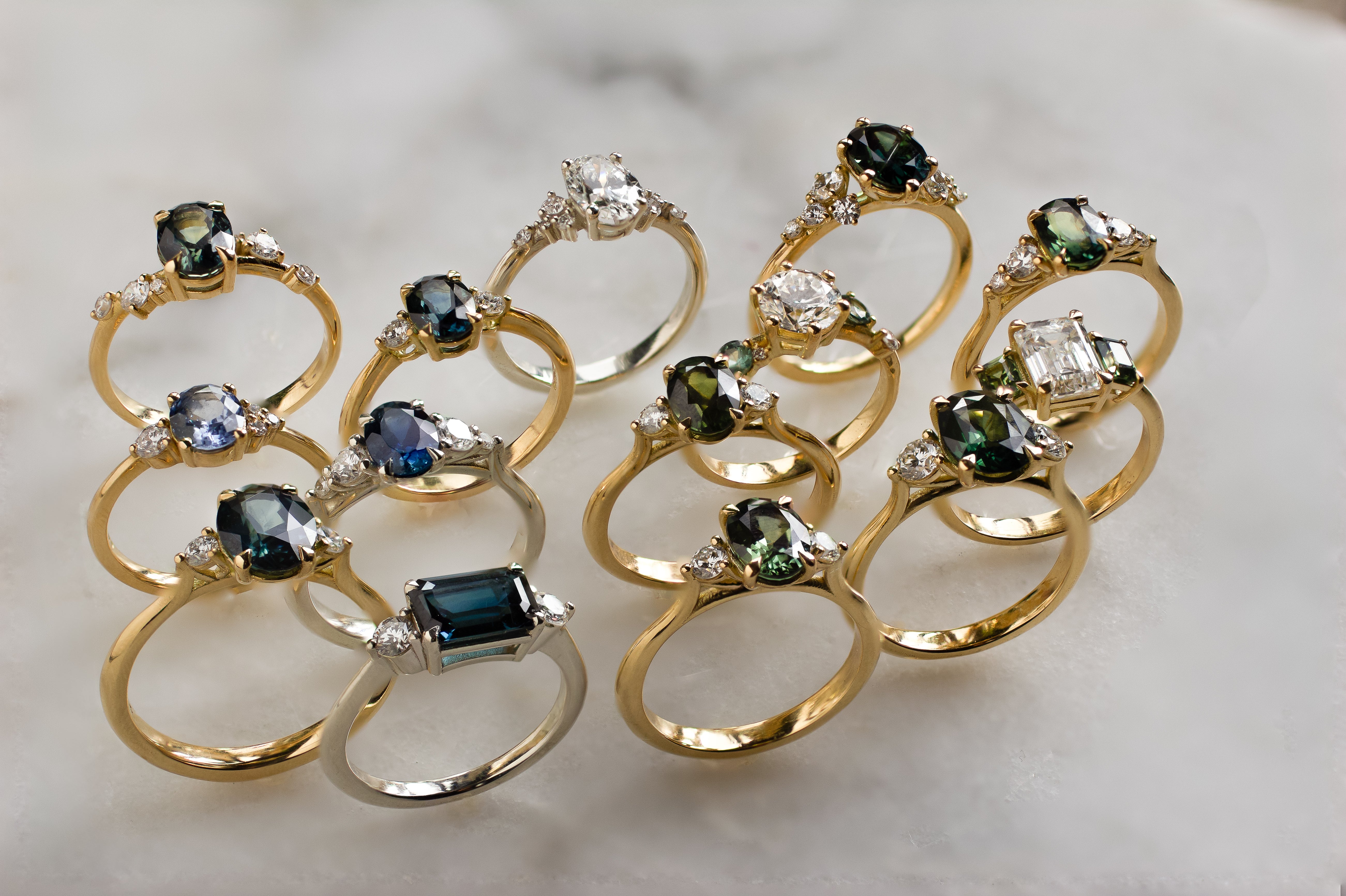 Gold rings with gemstones on a marble surface