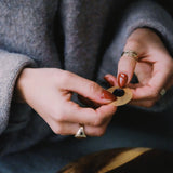 Person holding a small gold object with a dark background