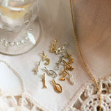 Gold jewelry with number charms on a lace tablecloth next to a candle