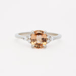 white gold engagement ring with a large orange gemstone and smaller diamonds on a white background