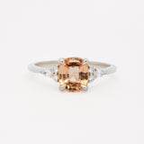 white gold engagement ring with a large orange gemstone and smaller diamonds on a white background