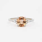 white gold engagement ring with a large orange gemstone and smaller diamonds on a white background