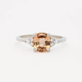white gold engagement ring with a large orange gemstone and smaller diamonds on a white background