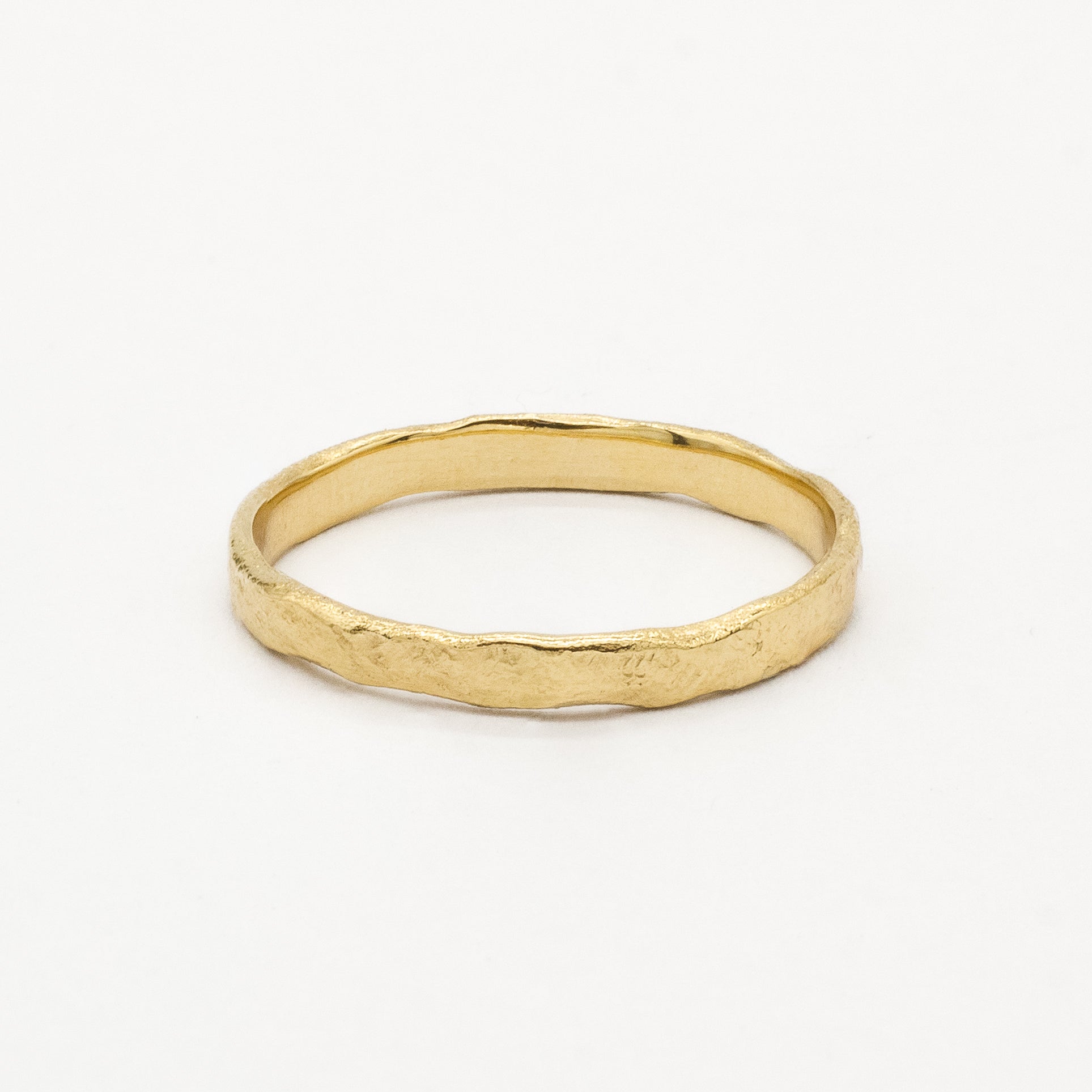 Gold slim 2mm rustic wedding ring with uneven edges and organic finish on a white background