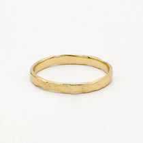 Gold slim 2mm rustic wedding ring with uneven edges and organic finish on a white background