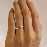 Gold organic rustic wedding ring with 2mm width on a hand with '9ct Yellow Gold' text