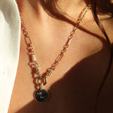 Necklace with an engraved pendant worn by a person, with a focus on the jewelry.