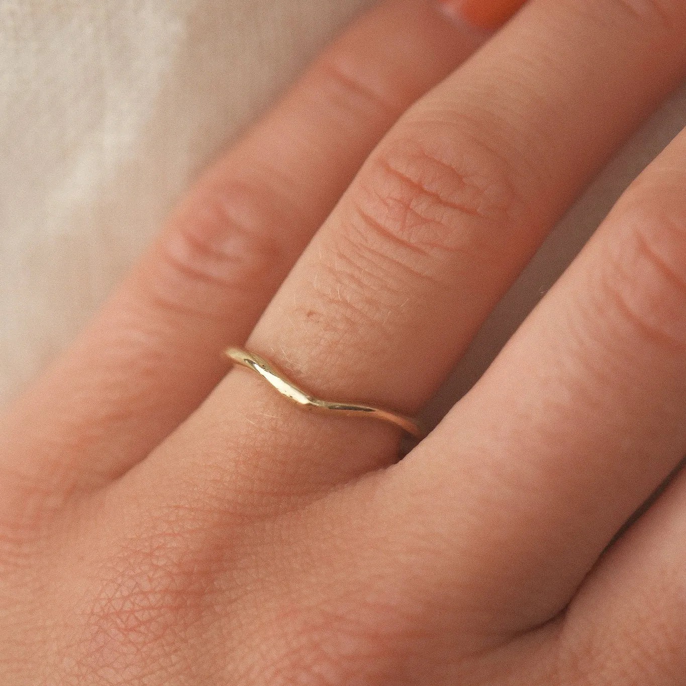 Gold ring on a person's finger with a soft background