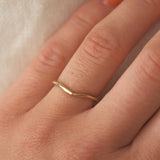 Gold ring on a person's finger with a soft background