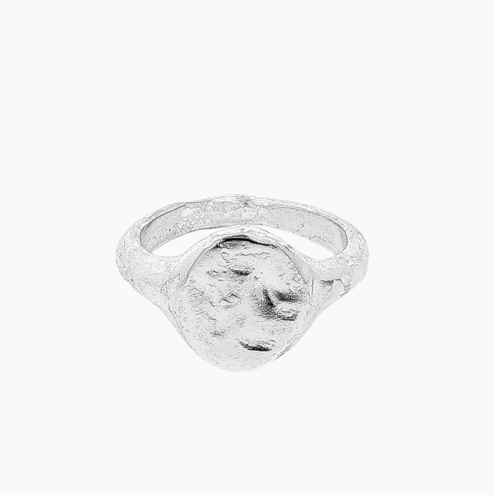 A textured sterling silver oval signet ring with a rough, organic-shaped face, shown on a plain off-white background.