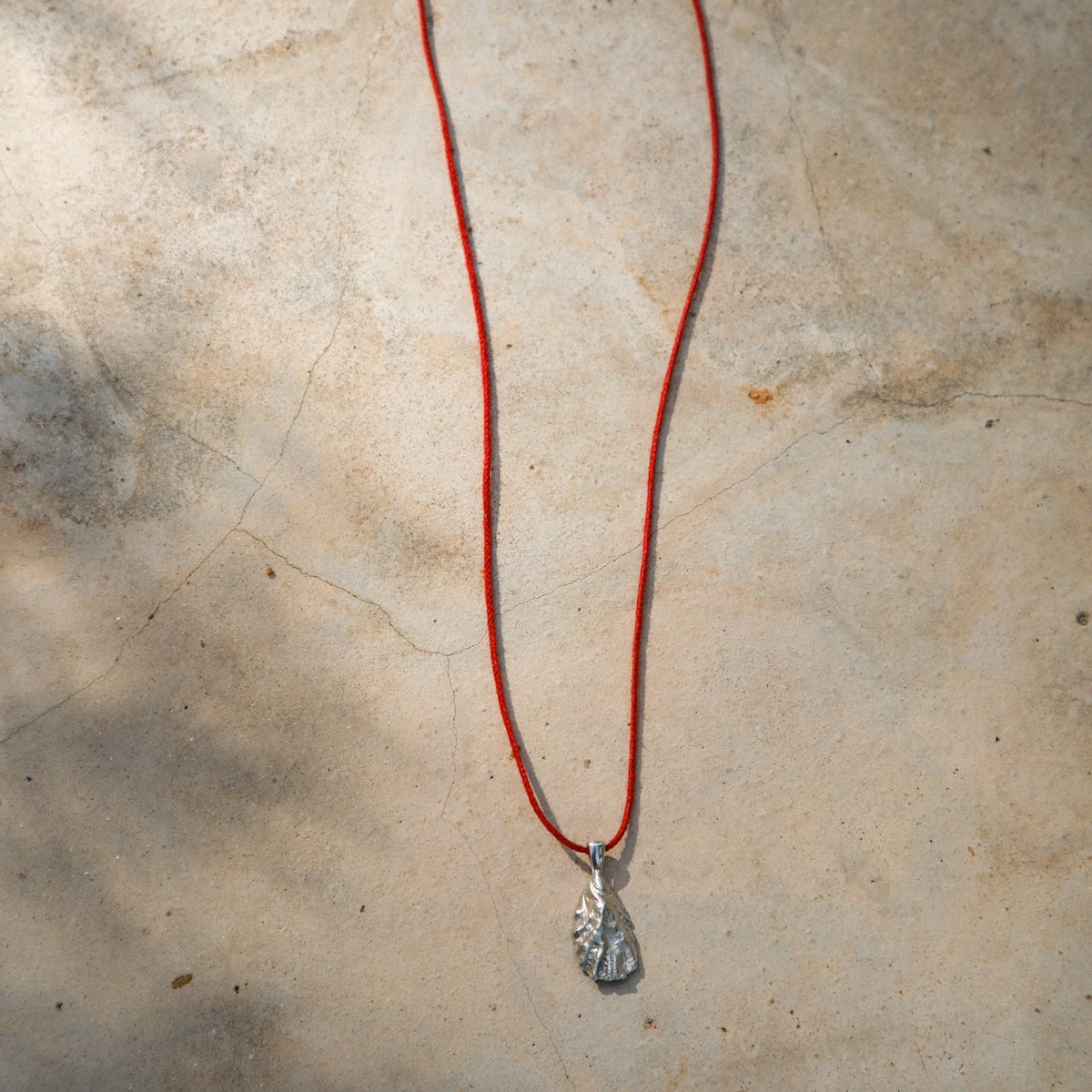 Necklace with a pendant on a textured beige surface