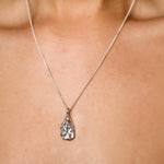 close up of oyster shell necklace on silver chain worn by model