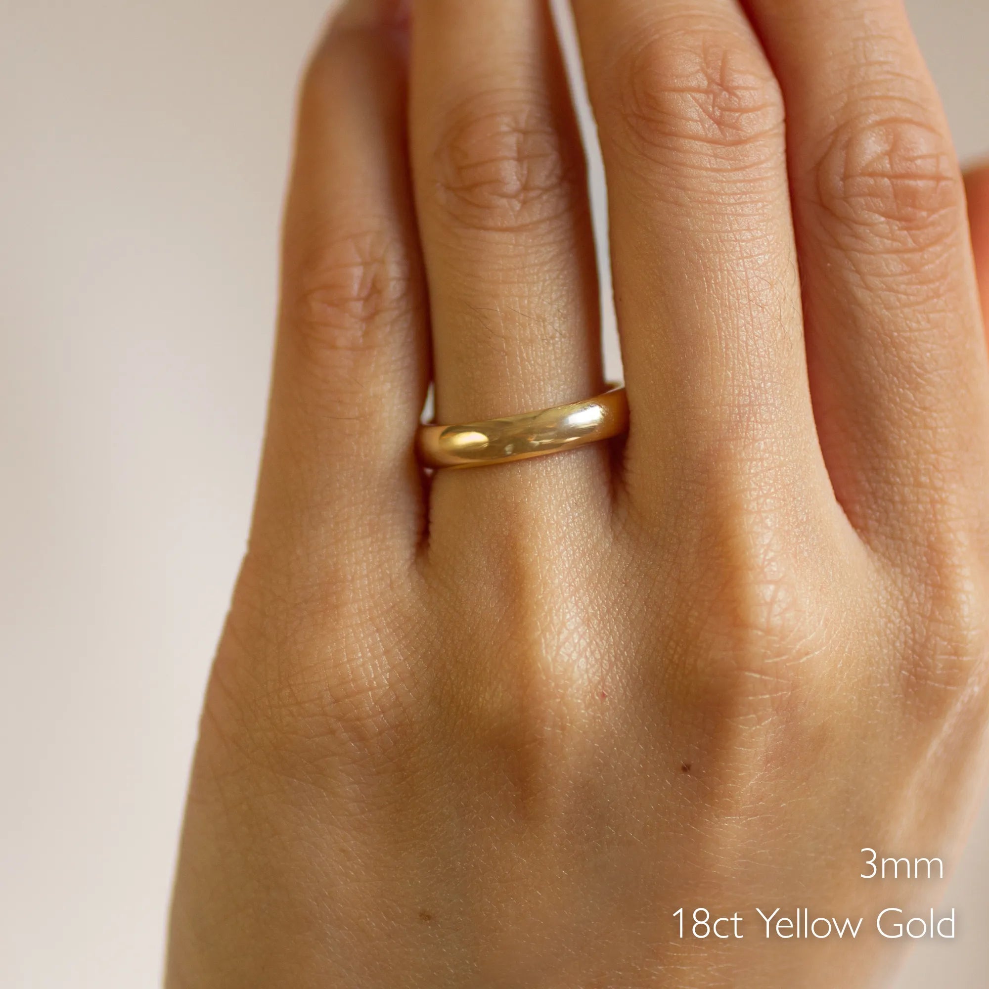 Gold d shape polished wedding ring on a hand with '3mm 18ct Yellow Gold' text