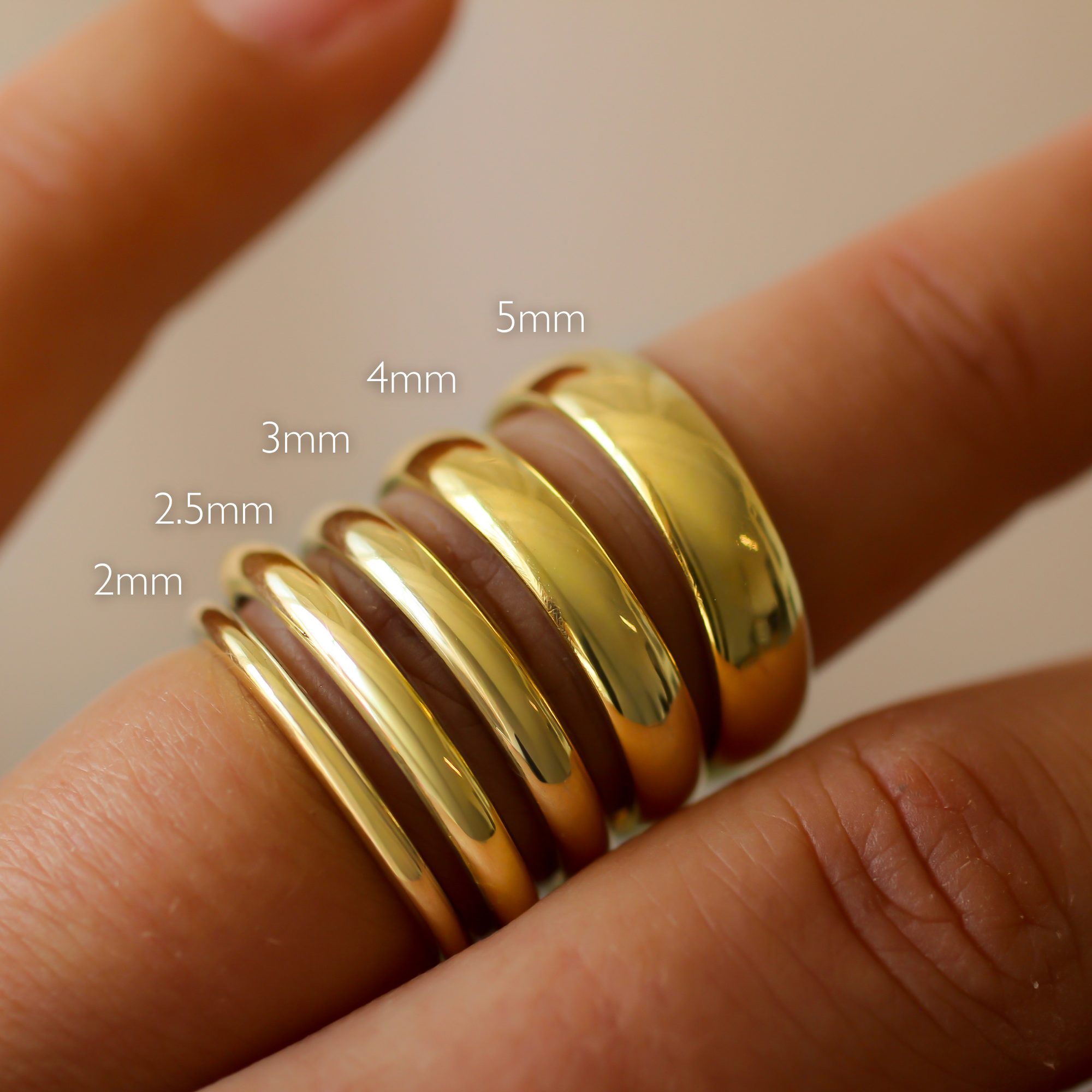 Gold d-shaped polished wedding rings on a finger with size measurements labeled 2mm 2.5mm 3mm 4mm 5mm