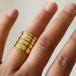 flat gold wedding rings on a finger with size markings 2mm 2.5mm 3mm 4mm and 5mm against a neutral background