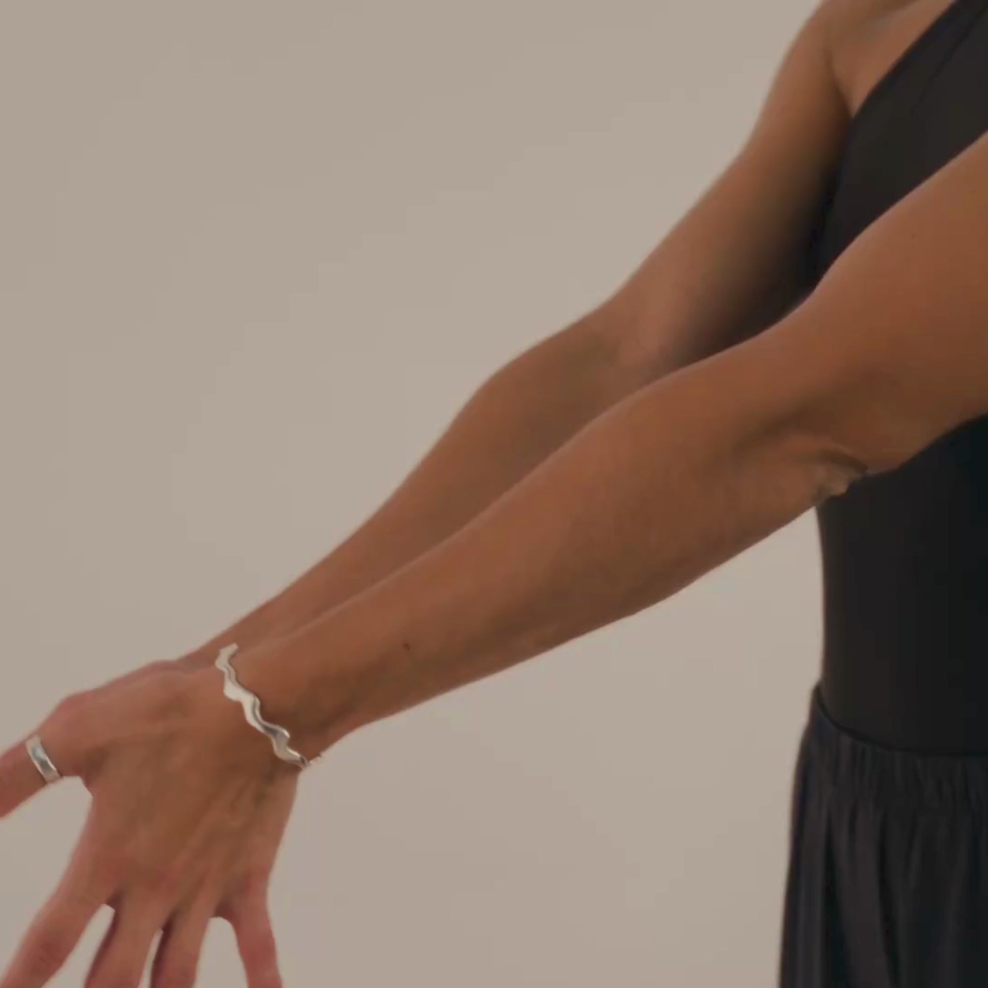 woman wearing one shoulder top and silver wavy bangle and ring doing yoga