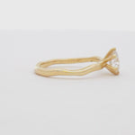 yellow gold solitaire engagement ring with round diamond and organic band spinning on a turntable